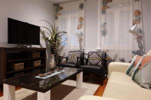 sala de estar con TV, 2 sillas y mesa en Céntrico y acogedor piso con garaje en A Coruña