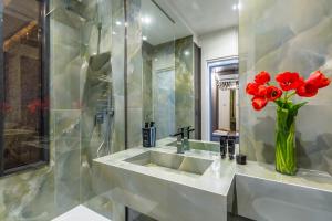 a bathroom with a sink with red flowers in a vase at Dei Martiri Suite in Naples +60 photos