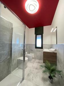 ein Bad mit einer roten Decke, einer Dusche und einem WC in der Unterkunft PanoramApartment in Desenzano del Garda