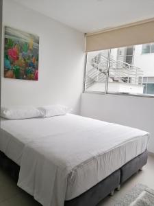 a white bedroom with a large bed and a window at Apartamento Lux Confort in Floridablanca