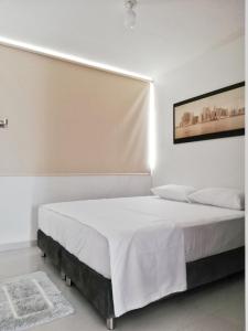 a white bedroom with a large bed with white sheets at Apartamento Lux Confort in Floridablanca