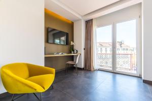 a yellow chair in a room with a large window at Dei Martiri Suite in Naples