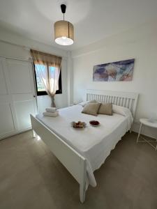 een witte slaapkamer met een groot bed met een bord eten erop bij Villa FIORENZA - 100 mt dal Mare in Castellammare del Golfo