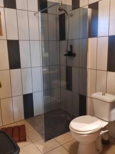 a bathroom with a toilet and a glass shower at Le Tri Haut de Bellevue - Bungalow Héliconia in Pointe-Noire