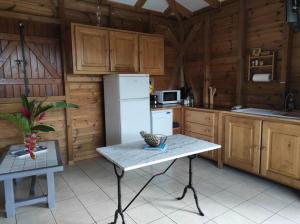 eine Küche mit einem weißen Kühlschrank und einem Tisch in der Unterkunft Le Tri Haut de Bellevue - Bungalow Héliconia in Pointe-Noire