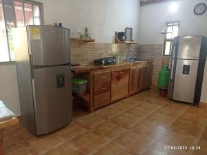 una cocina con nevera de acero inoxidable y armarios de madera en El ensueño, en San Bernardo del Viento