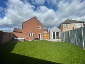 a yard with a brick house and a fence at DaisyChain Getaways at Chaney Rd in Wivenhoe