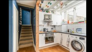 una pequeña cocina con armarios blancos y una escalera en Unique Character Filled, East London Flat en Londres