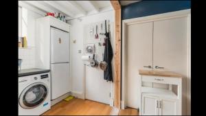 a kitchen with a washing machine and a refrigerator at Unique Character Filled, East London Flat in London