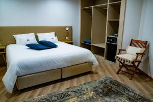 a bedroom with a large white bed and a chair at Loureiro B&B in São Pedro do Sul