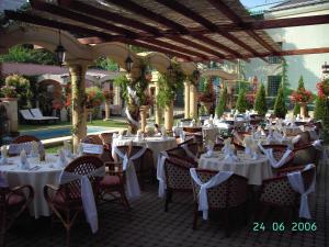 un restaurante con mesas y sillas blancas en un pabellón en Hotel Bow Garden, en Komárno