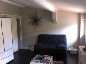 a living room with a couch and a clock on the wall at Coeur Vieil Antibes Plages à Pied in Antibes
