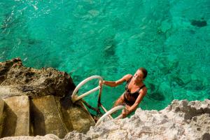 una mujer en el agua junto a algunas rocas en Hotel B Cozumel, en Cozumel