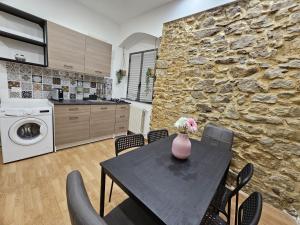 cocina y comedor con mesa y pared de piedra en Casa Vacirca, en Niscemi