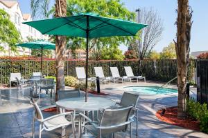 eine Terrasse mit Tischen, Stühlen und einem Sonnenschirm in der Unterkunft SpringHill Suites Bakersfield in Bakersfield