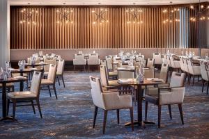 uma sala de jantar com mesas, cadeiras e luzes em The Westin Calgary Airport em Calgary