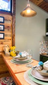 una mesa de madera con platos y gafas y una lámpara en Suite Cabaña Cantodeagua-Jacuzzi, en Villa de Leyva
