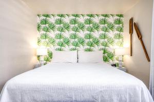 1 dormitorio con cama blanca y papel pintado tropical en Kona Bali Kai #174, en Kailua-Kona