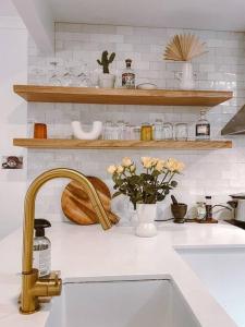 un bancone della cucina con lavandino, fiori e scaffali di Cosy Home Byron Bay a Byron Bay Altre 37 foto