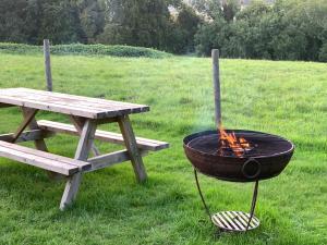 a grill next to a picnic table and a bench at Home Farm Radnage Glamping Bell Tent 8, with Log Burner and Fire Pit in High Wycombe