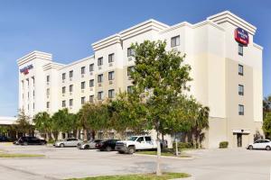 ein großes weißes Gebäude mit Autos auf einem Parkplatz in der Unterkunft Springhill Suites by Marriott West Palm Beach I-95 in West Palm Beach