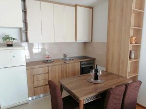 a kitchen with a wooden table with two wine glasses on it at Apartman Nomino in Zvornik