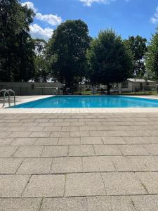 a large blue swimming pool with trees in the background at Freistehendes Ferienhaus am See Nähe Roermond in Heel
