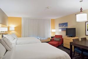 a hotel room with two beds and a desk and a television at TownePlace Suites by Marriott Garden City in Garden City
