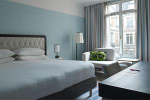 パリにあるパリス マリオット オペラ アンバサダー ホテルのベッドと椅子付きのホテルルーム