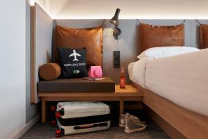 a bedroom with a bed and a table with a suitcase at Moxy Cologne Bonn Airport in Cologne