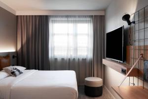 a hotel room with a bed and a television at Moxy Cologne Bonn Airport in Cologne