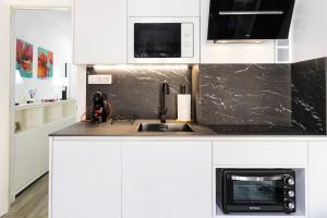 een witte keuken met een spoelbak en een magnetron bij El rinconcito de la playa, parking incluido in Sanxenxo