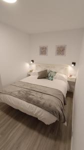 een witte slaapkamer met een groot bed met 2 nachtkastjes bij El rinconcito de la playa, parking incluido in Sanxenxo