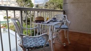 een tafel met twee stoelen en een hoed op een balkon bij El rinconcito de la playa, parking incluido in Sanxenxo