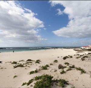a sandy beach with people in the water and the ocean at Apartamentos Albaula 5 in Cotillo