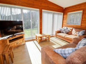 uma sala de estar com um sofá e uma televisão de ecrã plano em Watersview Lodge em Leek