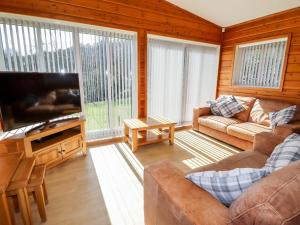 a living room with a couch and a flat screen tv at Watersview Lodge in Leek