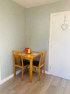 una mesa de comedor con 2 sillas y un bol de fruta. en Malvern Apartment, en Derry Londonderry