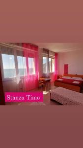 Schlafzimmer mit rosa Vorhängen, einem Bett und einem Tisch in der Unterkunft Perla del Levante Hostel in Framura