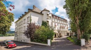 ein Gebäude mit einem roten Auto, das davor geparkt ist in der Unterkunft Rheinhotel Dreesen in Bonn