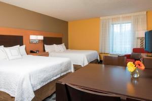 ein Hotelzimmer mit 2 Betten und einem Tisch mit Blumen darauf in der Unterkunft TownePlace Suites by Marriott Kalamazoo in Portage