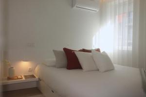 uma cama branca com almofadas brancas e uma janela em Sweet Dreams in Braga em Braga