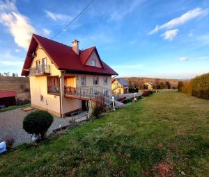 a house with a red roof on a green field at Cichy Potok in Polańczyk