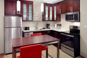 a kitchen with wooden cabinets and a wooden table with red chairs at Residence Inn by Marriott Columbus OSU in Columbus