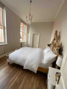 um quarto com uma grande cama branca e pisos em madeira em Luxury 2 BD, 2 BA on private gated Chigwell park em Chigwell