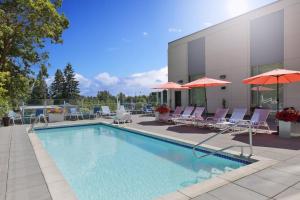 a swimming pool with chairs and umbrellas next to a building at Four Points by Sheraton Seattle Airport South in SeaTac