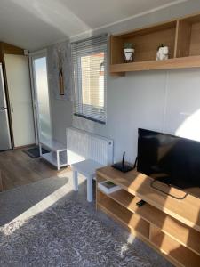 a living room with a flat screen tv and a table at Stylish 3 Bedroom caravan near the Beach in Walton-on-the-Naze