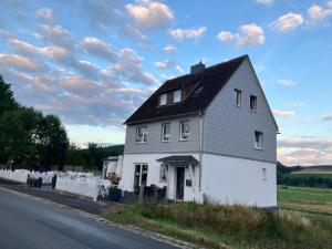 una casa blanca con un techo negro a un lado de la carretera en Mellys Café & Store, en Einbeck