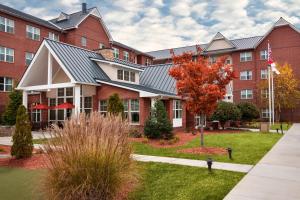 Residence Inn by Marriott Greensboro Airport في جرينسبورو: مبنى من الطوب الأحمر كبير مع شجرة في الفناء