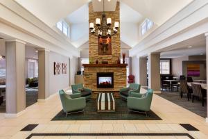 a lobby with a fireplace and chairs and a table at Residence Inn by Marriott Greensboro Airport in Greensboro